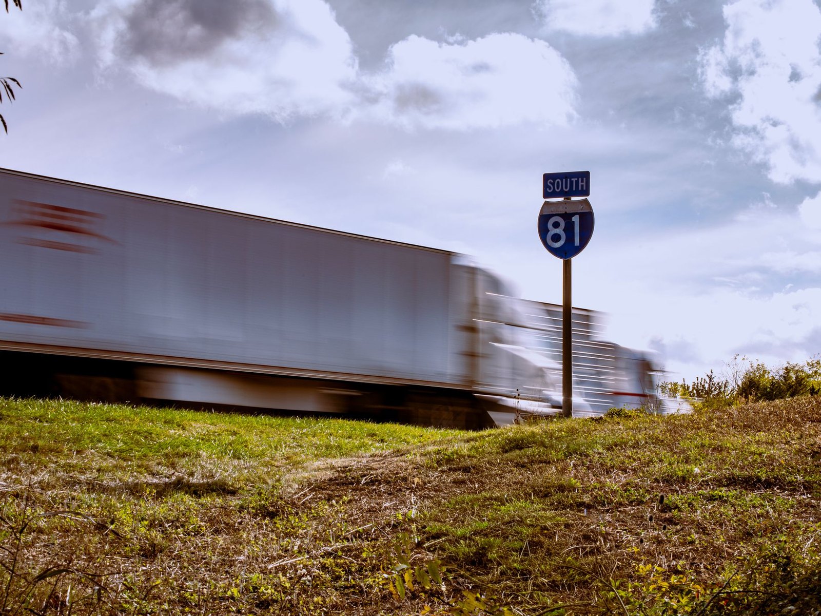 A tractor-trailer moving at speed past an Interstate 81 South highway marker